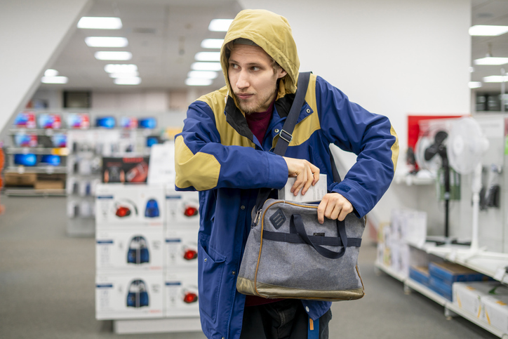 shoplifter in the electronic store supermarket stealing new gadget f